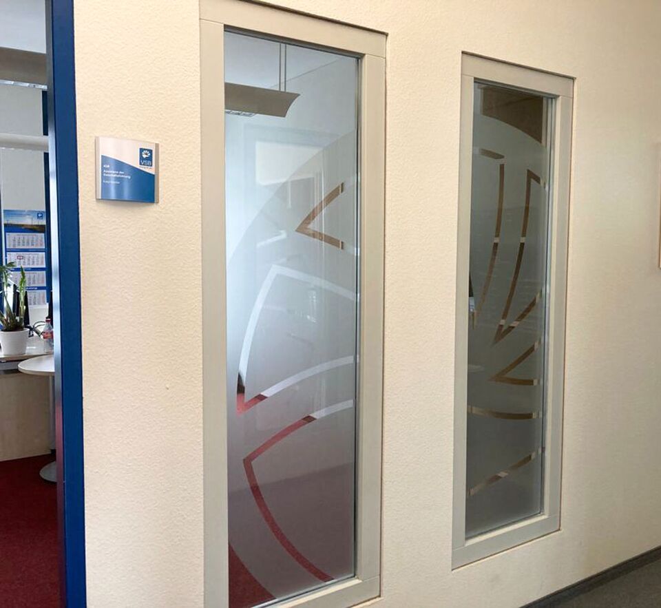 Moderne Glaswand im Büro, die mit einer dekorativen, halbtransparenten Sichtschutzfolie im geometrischen Design beklebt ist.