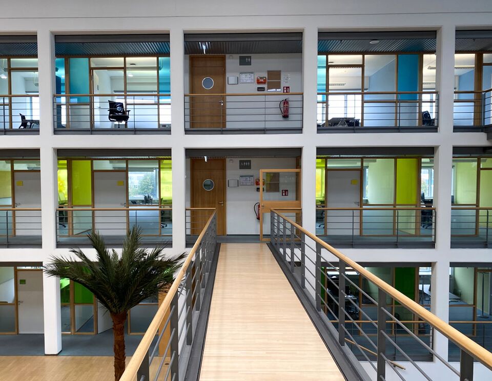 Glaswand in einem großen Bürobereich, die mit einer farbigen halbtransparenten Sichtschutzfolie versehen ist.