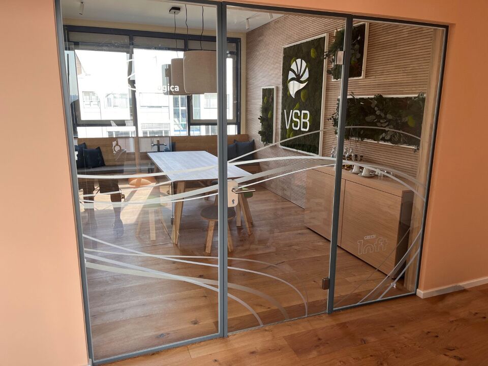 Eine moderne Sichtschutzfolie, die auf eine Glastrennwand im Büro aufgebracht wurde, um die Privatsphäre zu gewährleisten.