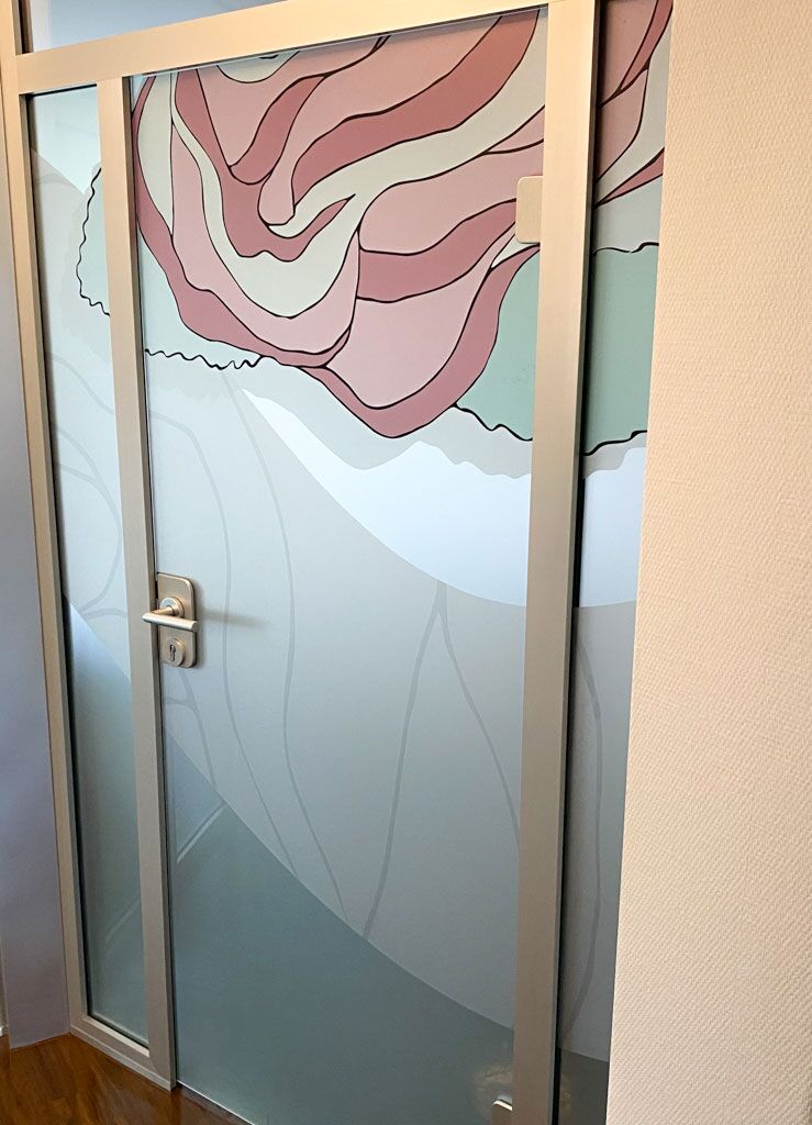Glastür in einer Praxis, die mit einer floral gestalteten Sichtschutzfolie dekoriert ist.